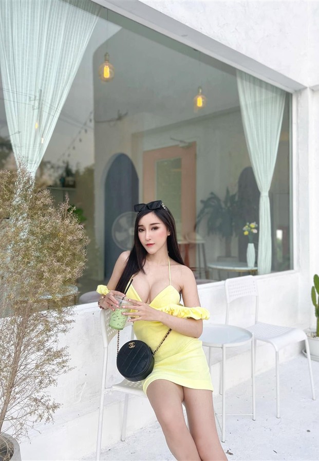 ชุดเดรสสีเหลืองนั่งพิงผนังขาวในลุคเรียบง่าย