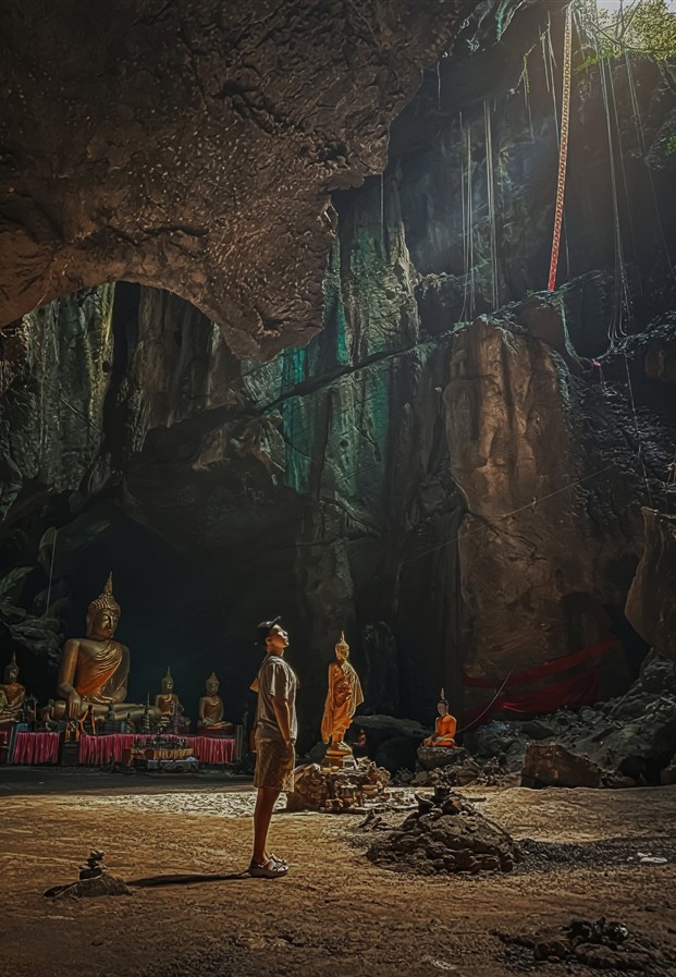 ยืนอยู่ในถ้ำที่ประดิษฐานพระพุทธรูป