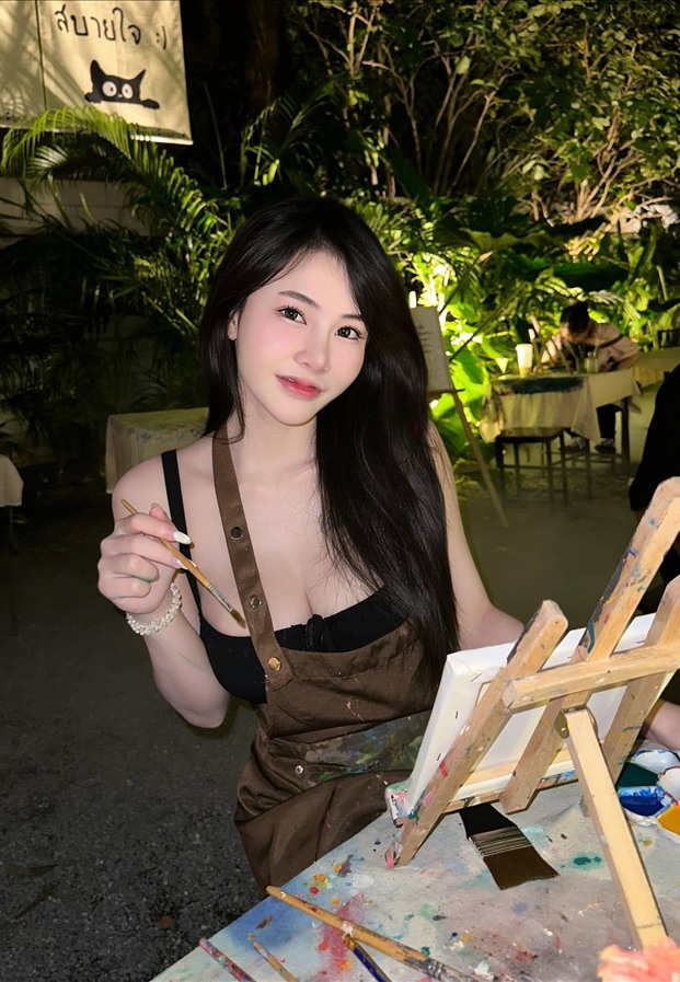 Cholthida Phonsan เอี๊ยมสีน้ำตาลถือพู่กันข้างขาตั้งวาดรูปยามค่ำ