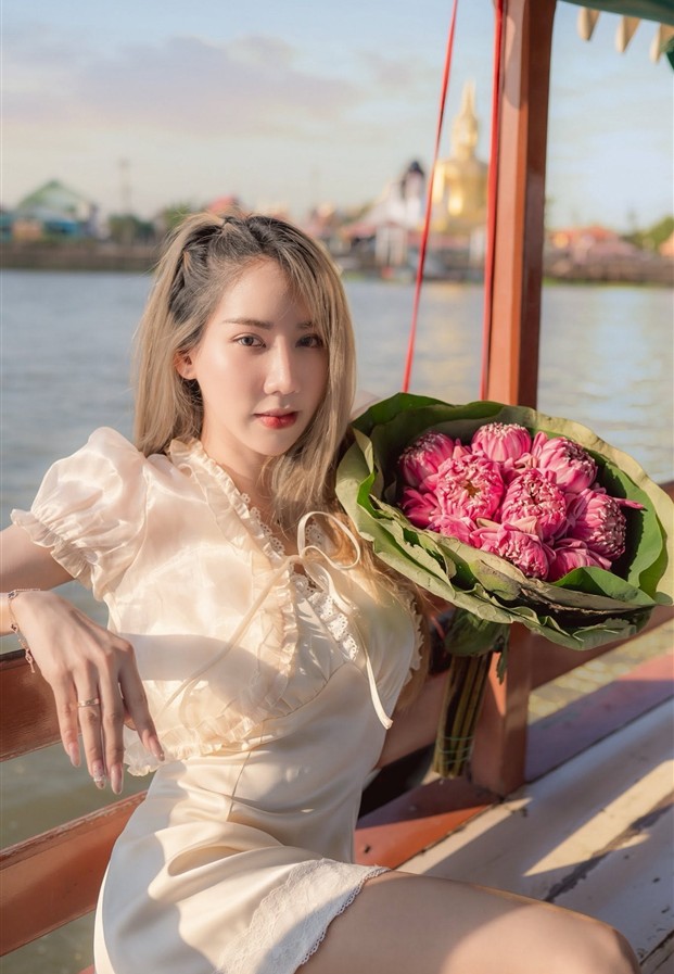 Nantana Jumpadib เดรสสั้นสีครีมถือช่อดอกบัวชมพูบนเรือไม้